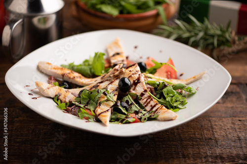 Roasted chicken with rocket salad in white bowl on wood table