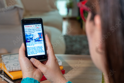 Online news on a mobile phone. Close up of the page of a businesswoman reading news or articles on a smartphone screen application. Smartphone with hand. Mockup website. Newspaper and Internet portal.