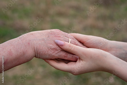 The hand of an elderly woman and the hands of a teenage girl. © FO_DE