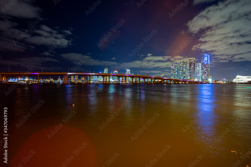 Miami, Florida skyline at sunset. Miami city skyline panorama at dusk with urban skyscrapers and bridge over sea with reflection.
