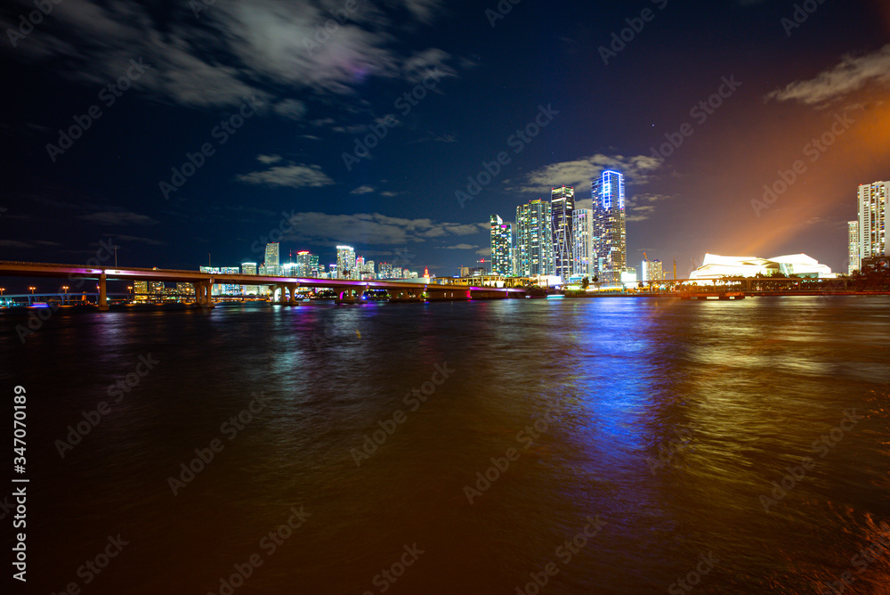 Miami Skyline Panorama after sunset. Miami city skyline panorama at dusk with urban skyscrapers and bridge over sea with reflection. Miami Florida.