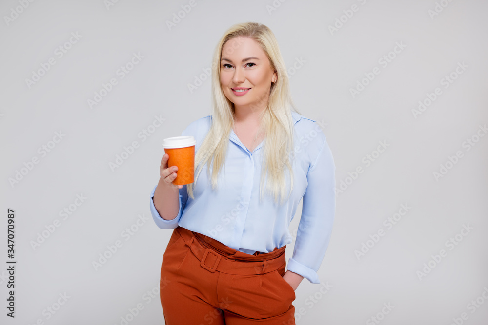 portrait of beautiful plus size blonde woman with paper cup of coffee over gray portrait of beautiful plus size blonde woman with paper cup of coffee over gray
