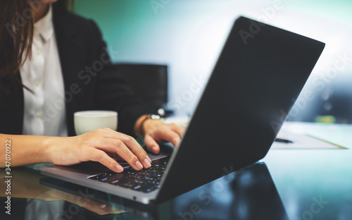 A businesswoman using and typing on laptop computer keyboard while working in office