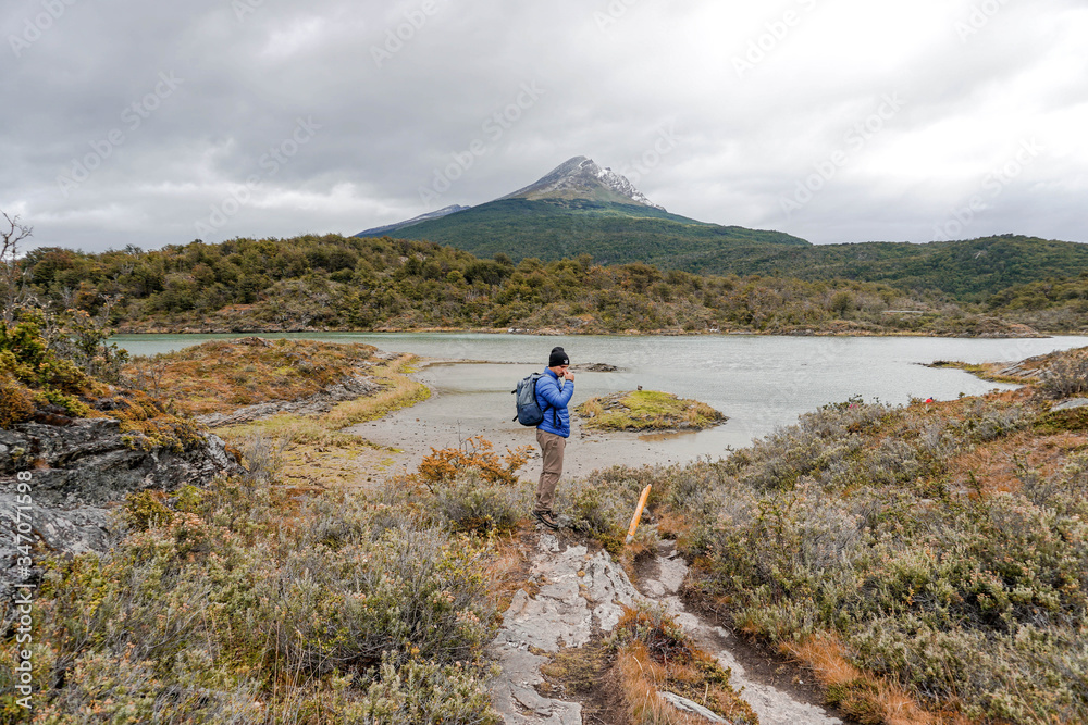 Fototapeta premium Young male with a backpack in Patagonia, Argentina. Hiker hiking rocky mountain surrounding by clouds. Tourism, travelling and healthy lifestyle concept. 