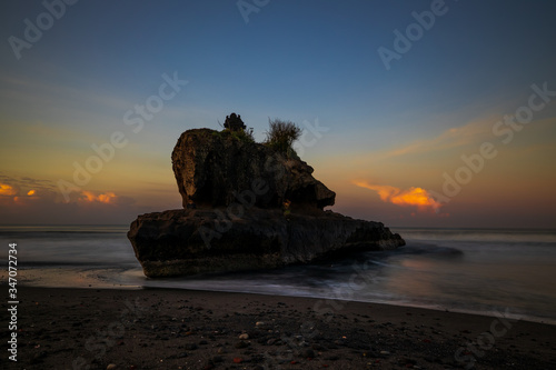 Amazing seascape. Sunrise at Yeh Gangga beach. Rock in the ocean. Waves captured with slow shutter speed. Long exposure with soft focus. Tabanan, Bali.