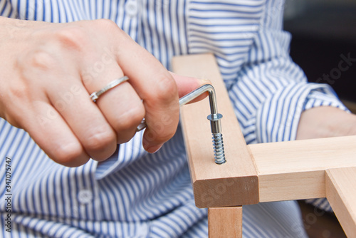 woman hands assembling wooden furniture with tools during quarantine isolation.