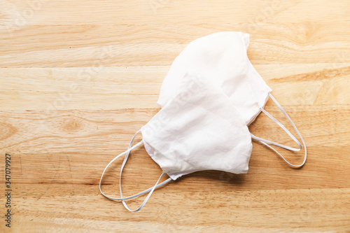 homemade white cloth masks for protection against coronavirus (COVID-19) on wooden table mediumshot