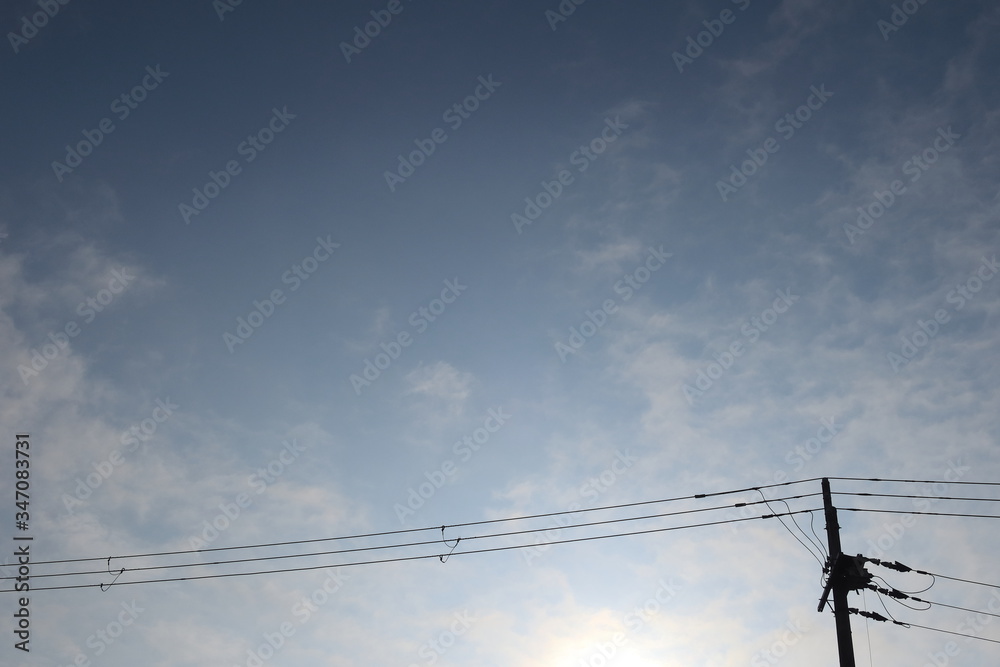 青空を背景とした電柱と電線のシルエットの写真