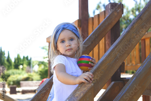 little blue-eyed girl plays in the playground