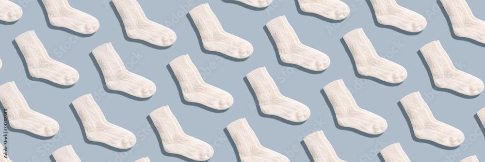 Pair of white woolen knitted socks pattern on grey background. Top view. Copy space. Creative design for packaging. Christmas and New Year cozy holiday composition. Winter weather Pair of white woolen knitted socks pattern on grey background. Top view. Copy space. Creative design for packaging. Christmas and New Year cozy holiday composition. Winter weather
