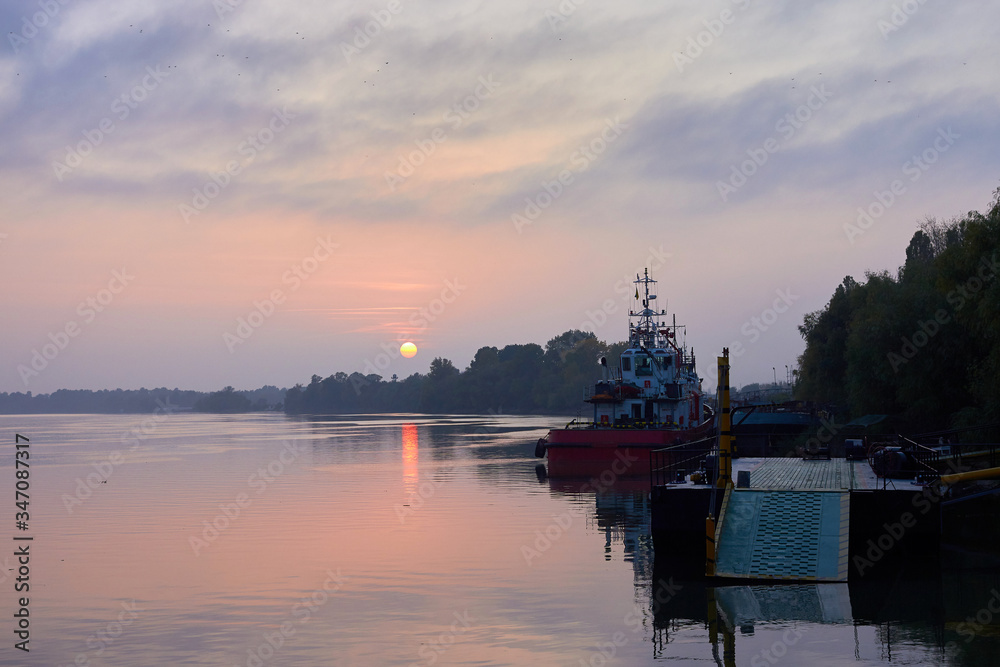 Beautiful autumn sunset over river with ship