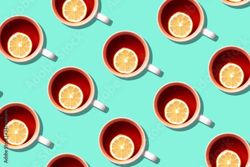Pattern of tea cups with lemon on blue background. Top view. Copy space. Creative design for packaging. Autumn or winter season concept