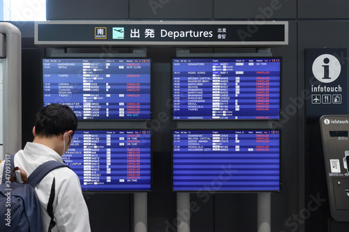 COVID-19のパンデミックにより、多くの航空便が欠航となった成田空港で出発案内板を見る男性