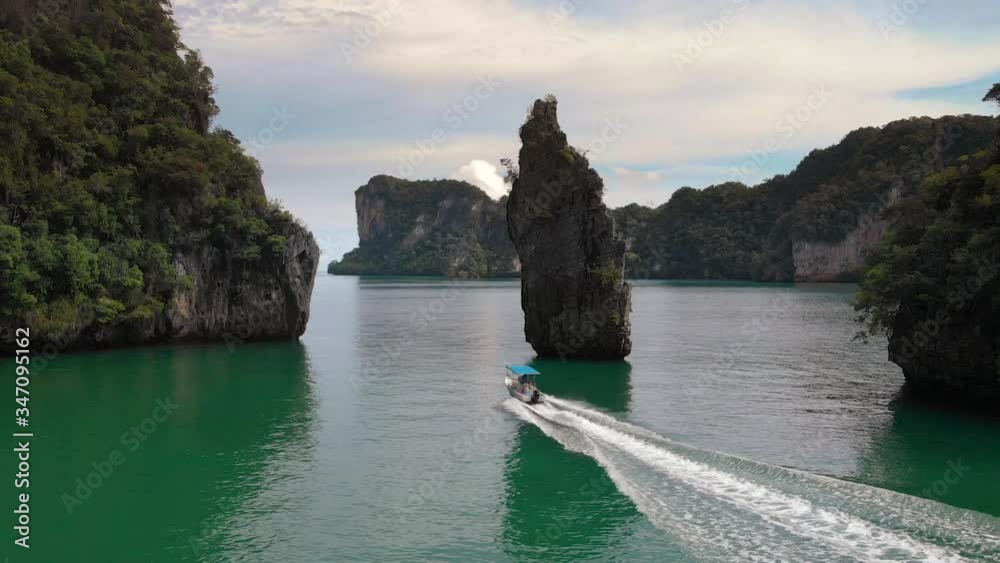 Drone pushing forwards following a speed boart departing from a secret bay at Pang Na Bay near Koh Yao Noi island in Thailand.