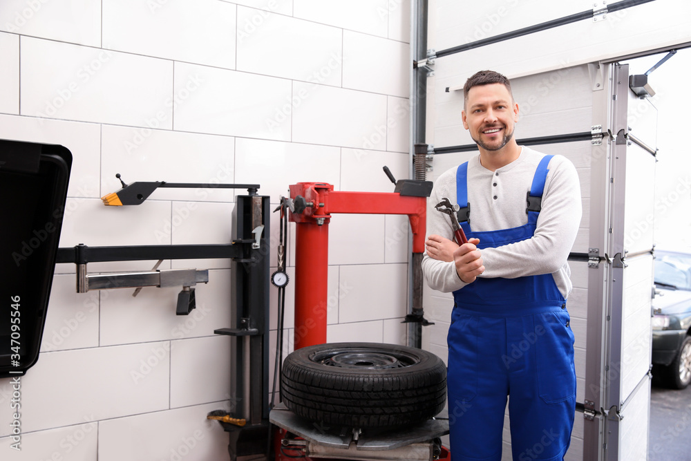 Man near tire fitting machine at car service Man near tire fitting machine at car service