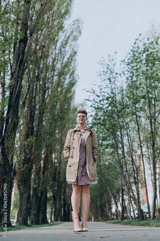 a girl with short blond hair walks around the city in a raincoat blooming in spring a girl with short blond hair walks around the city in a raincoat blooming in spring