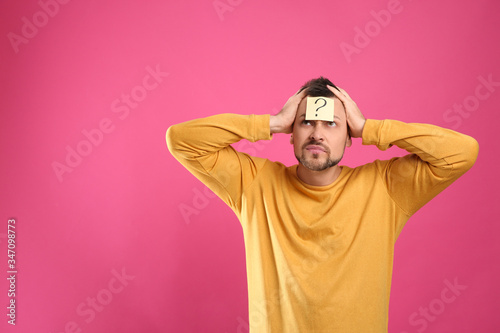 Emotional man with question mark on pink background, space for text © New Africa