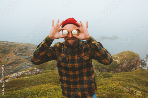 Joyful man having fun outdoor travel vacation lifestyle comic positive emotions guy holding sea urchins shells like big eyeballs photo