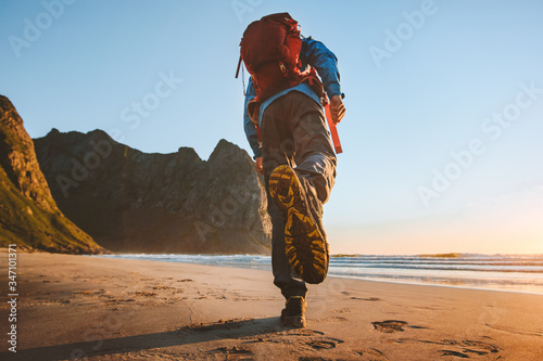 Man with backpack trail running on beach adventure travel vacations active healthy lifestyle outdoor exploring Norway sole sport shoes feet view