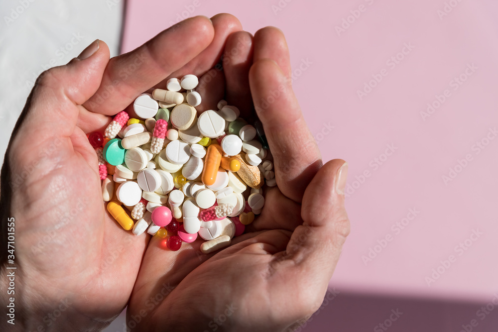 man holding pills on hand.Overdose of medication. A lot of pills spilled on table. Attempt of suicide.Economic crisis and medicine problems. Virus pandemic.Copy space man holding pills on hand.Overdose of medication. A lot of pills spilled on table. Attempt of suicide.Economic crisis and medicine problems. Virus pandemic.Copy space