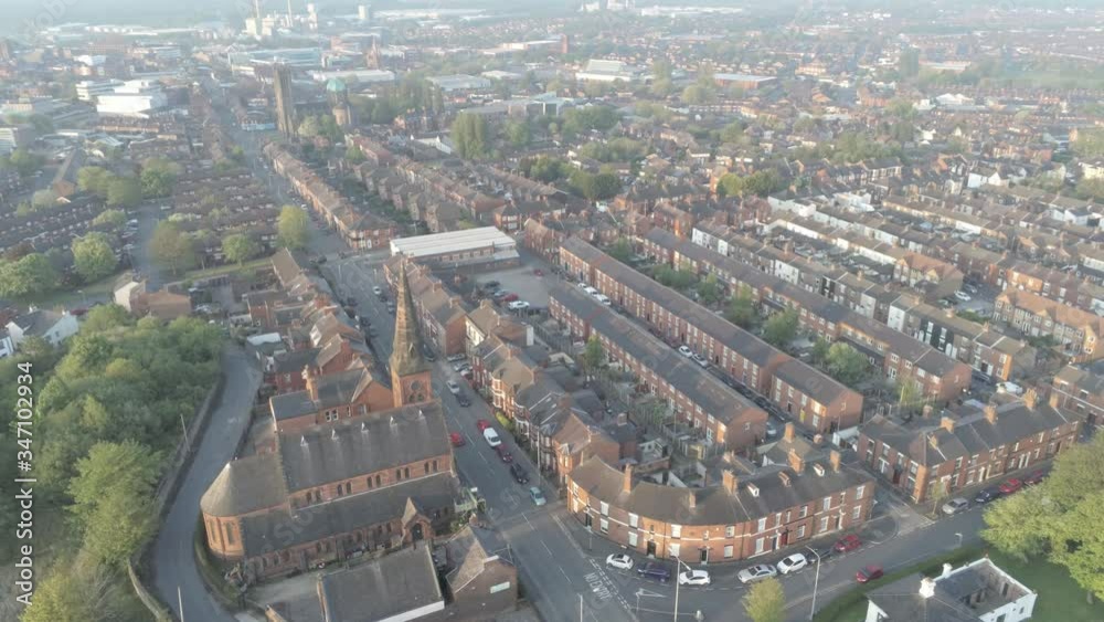 Sunrise drone view orbit left above England village houses and village church with steeple Sunrise drone view orbit left above England village houses and village church with steeple