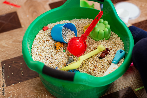 grains and cereals are mixed in a bowl with small toys, toys for autism, autism, child development, sensory activities photo