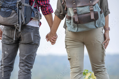 A young couple standing and holding hands on the top of the hill