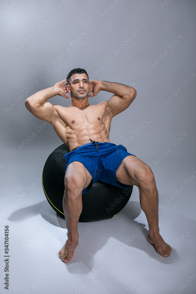 Obraz premium Attractive young man using exercise ball. Attractive young man exercising abs .