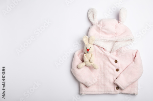 Child's clothes and toy bunny on white background, top view