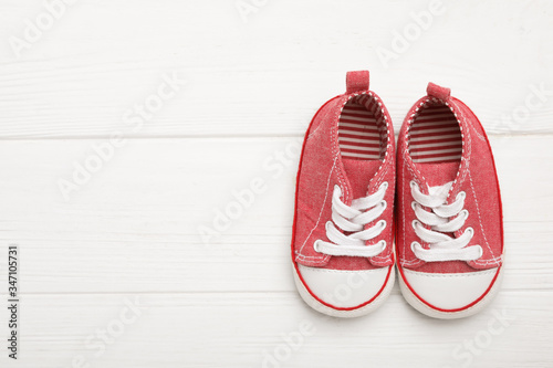 Top view of child's booties on white wooden background, space for text