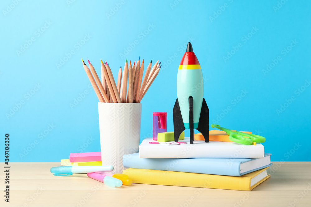 Obraz premium Bright toy rocket and school supplies on wooden table