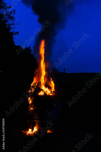 A bonfire blazing in a barrel against a dark blue night sky in the background