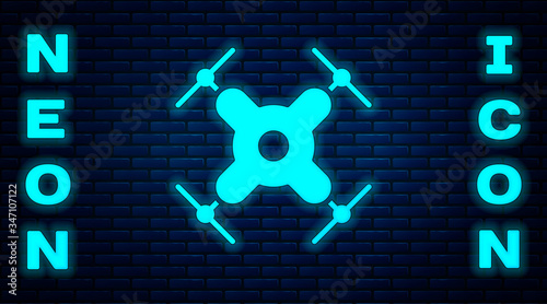 Glowing neon Drone flying icon isolated on brick wall background. Quadrocopter with video and photo camera symbol.  Vector Illustration