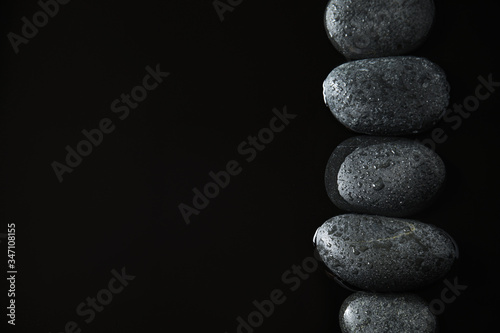 Stones in water on black background  flat lay with space for text. Zen lifestyle