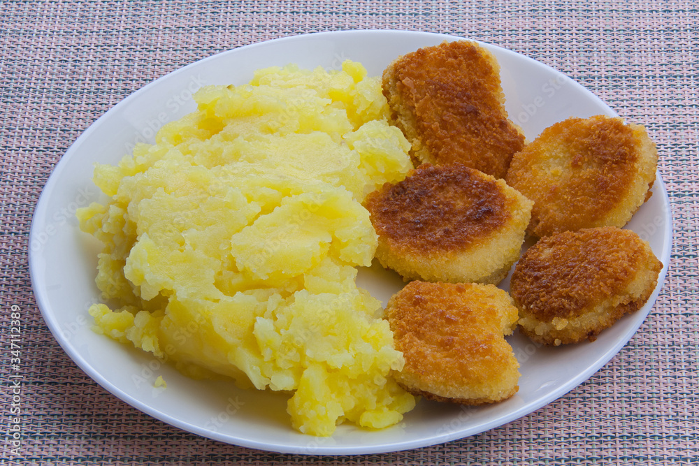 Boiled mashed potatoes on a plate with chicken nuggets on table Boiled mashed potatoes on a plate with chicken nuggets on table
