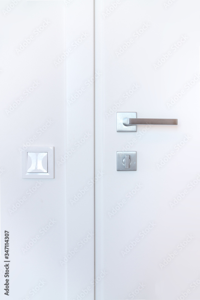 white closed door with a metal handle and hardware on a white wall background white closed door with a metal handle and hardware on a white wall background