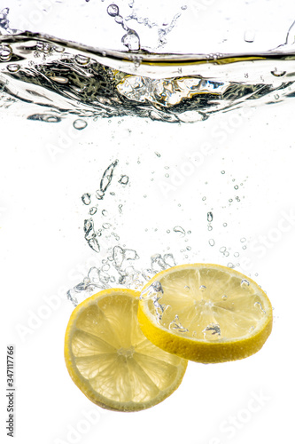 whole and sliced lemon falling under water with a splash and bubbles on a white or black background