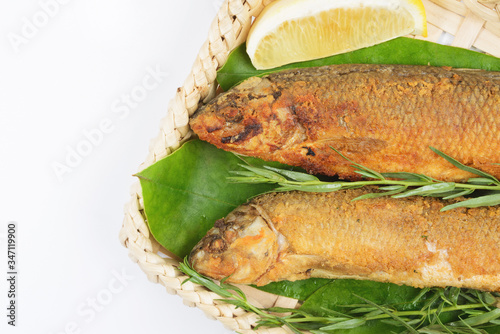 Grilled fish in a wicker basket with greens on a white background. photo