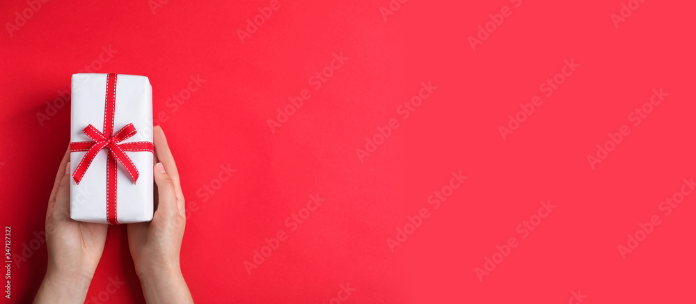 Woman with gift box and space for text on red background, top view. Banner design - obrazy, fototapety, plakaty 