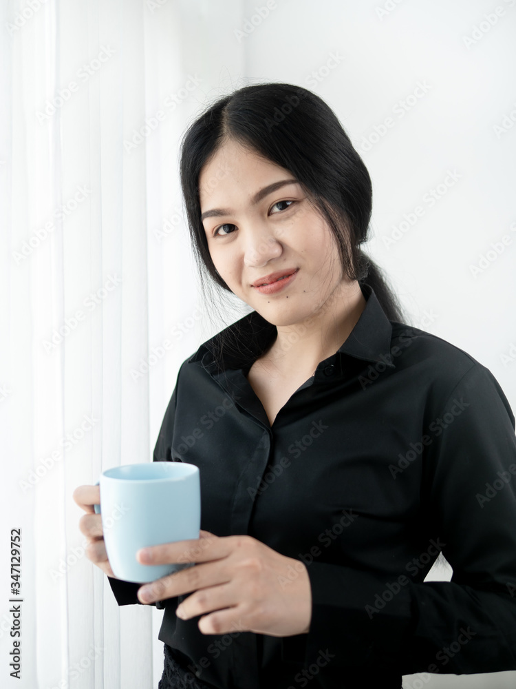 Asian business woman drinking coffee near window in the morning, lifestyle concept.