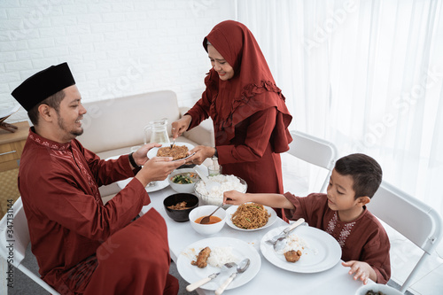 Muslim family sit to eat when breaking fast together at home