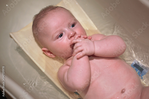 Infant baby boy washed in small bath tub, view from above