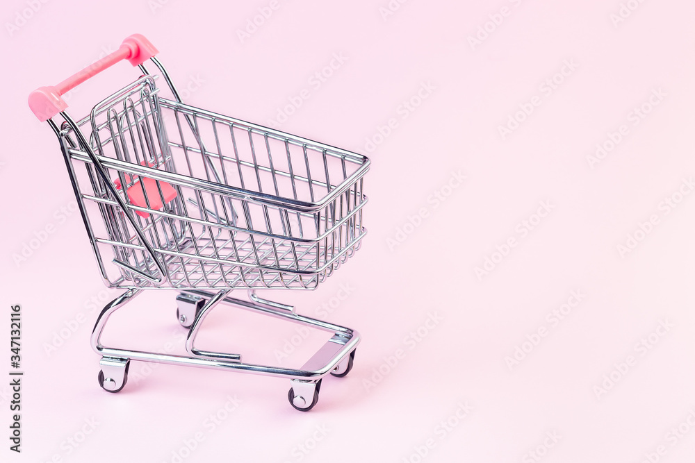 Small empty shopping cart on a pink background, copy space, horizontal Small empty shopping cart on a pink background, copy space, horizontal