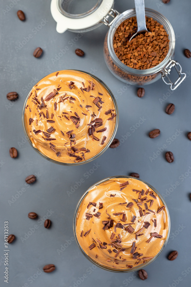 Dalgona coffee with ice garnished with grated chocolate, trendy korean drink on a dark gray background, vertical, top view, closeup Dalgona coffee with ice garnished with grated chocolate, trendy korean drink on a dark gray background, vertical, top view, closeup