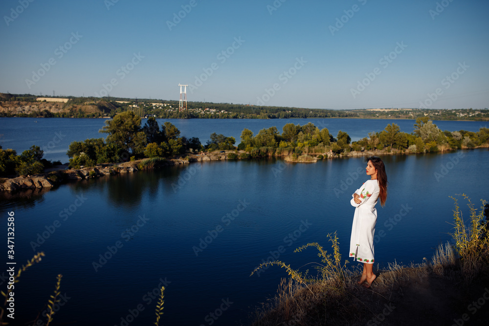 Obraz premium girl in a long dress on a background of water, lake career