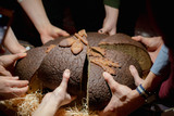 Multiple young hands share brown round bread