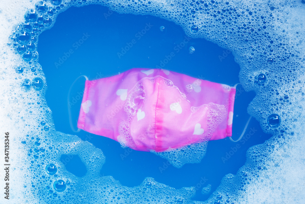 Pink cloth masks soak in powder detergent water dissolution before washing. Hygiene coronavirus (Covid-19) protection concept