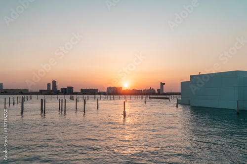 Abu Dhabi Cityscape SUNSET skyline  with buildings  river water and skyscrappers. Beautiful Emirates City at dusk. Orange sun.