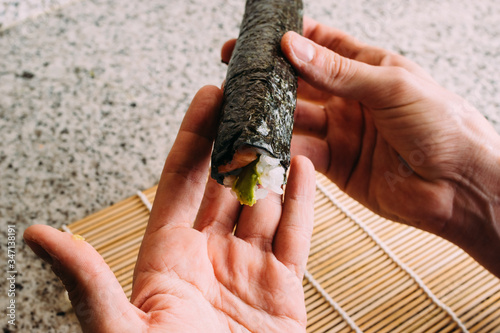 Roll maki sushi exposed on hands after have rolled. Cooking japanese dish homemade.
