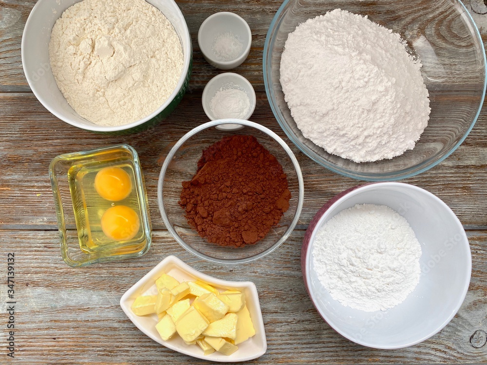 Grocery set for baking chocolate cookies on a wooden background, ready for a recipe step by step.